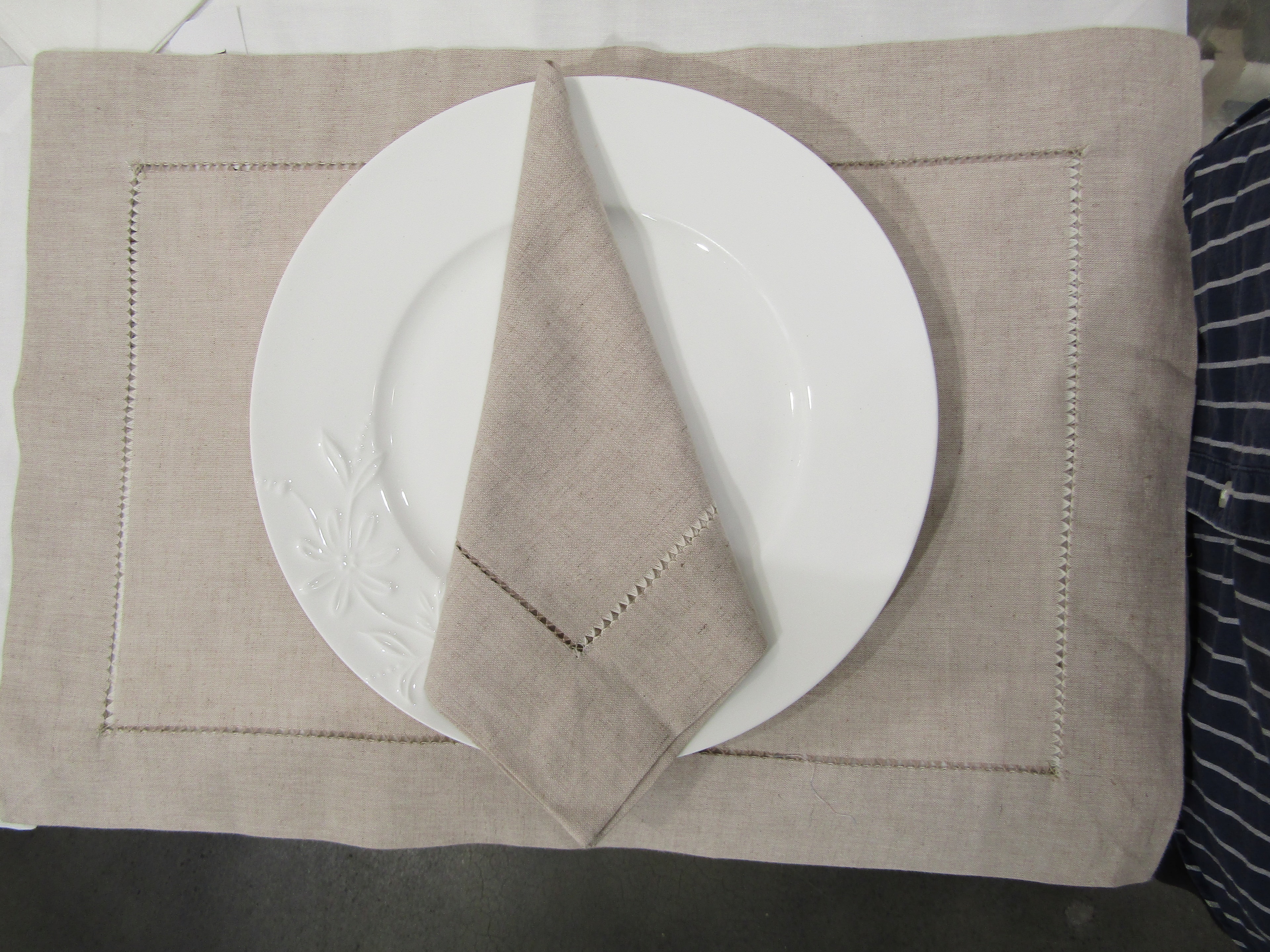 Linen mix dinner napkin folded on matching hemstitched placemat
